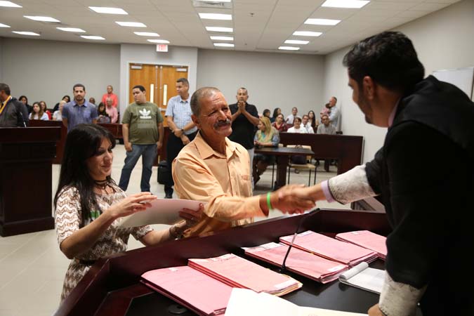 El Juez Administrador de la Región de Caguas, Hon. Ricardo Marrero Guerrero, felicita a José quien completó el programa con la ayuda de la Oficial de Servicios Alternos de Recuperación, Maribel Ríos Arroyo.