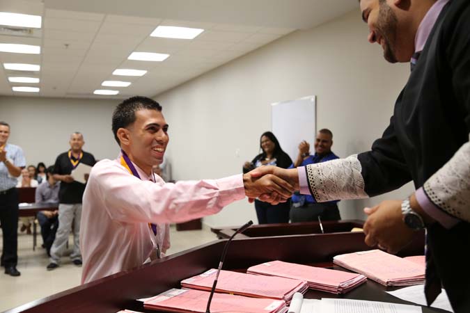 El Juez Administrador de la Región de Caguas, Hon. Ricardo Marrero Guerrero, entregó medallas y certificados a todos los participantes que terminaron el proceso. En la foto, Yamil se despide del Juez Administrador mientras los presentes aplauden su logro.